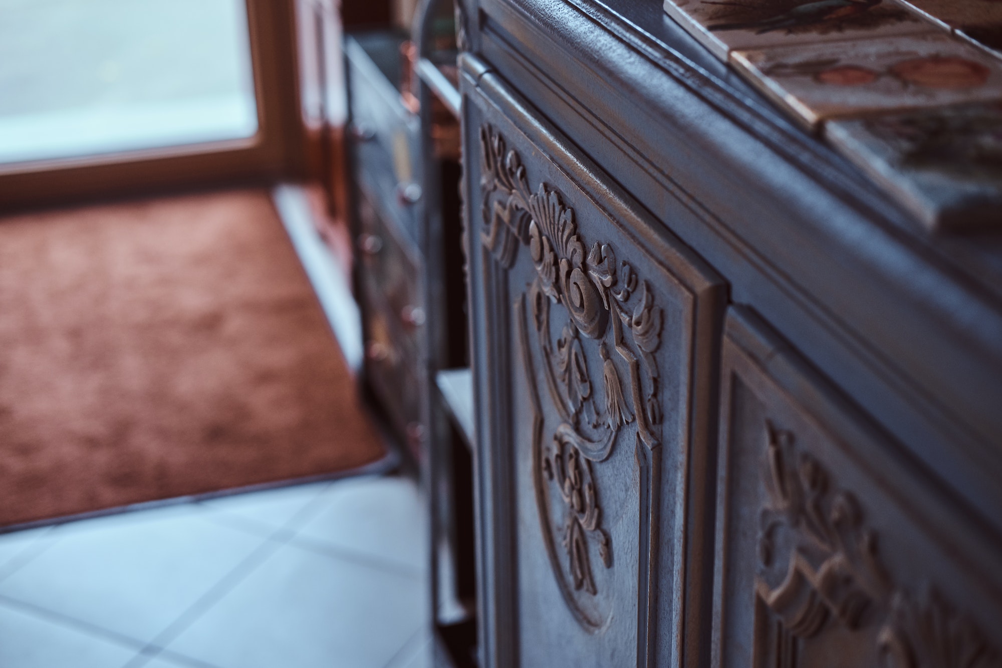 Close-up photo of hand-painted tiles on a vintage bookshelf.